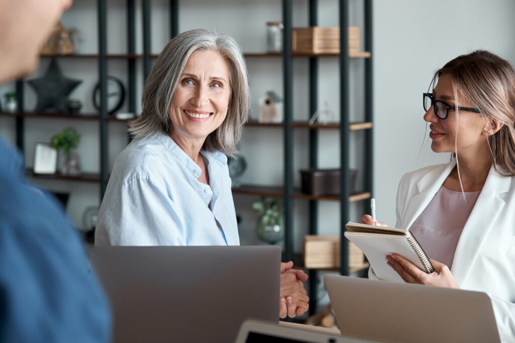 Smiling mature female mentor teacher communicating with students or interns.